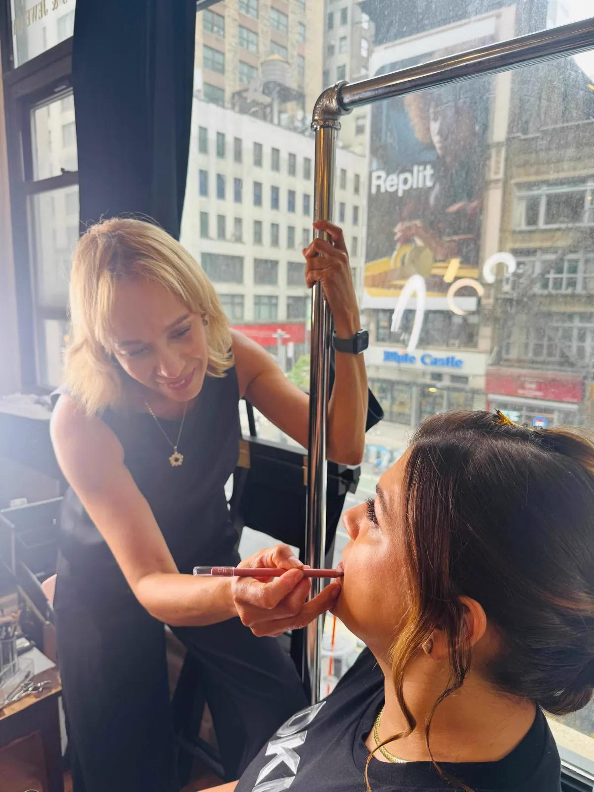 Yesi applying lipstick backstage, Midtown Manhattan view